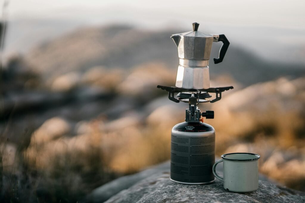 A close-up of a coffee pot on a camping stove outdoors, evoking an adventure vibe.